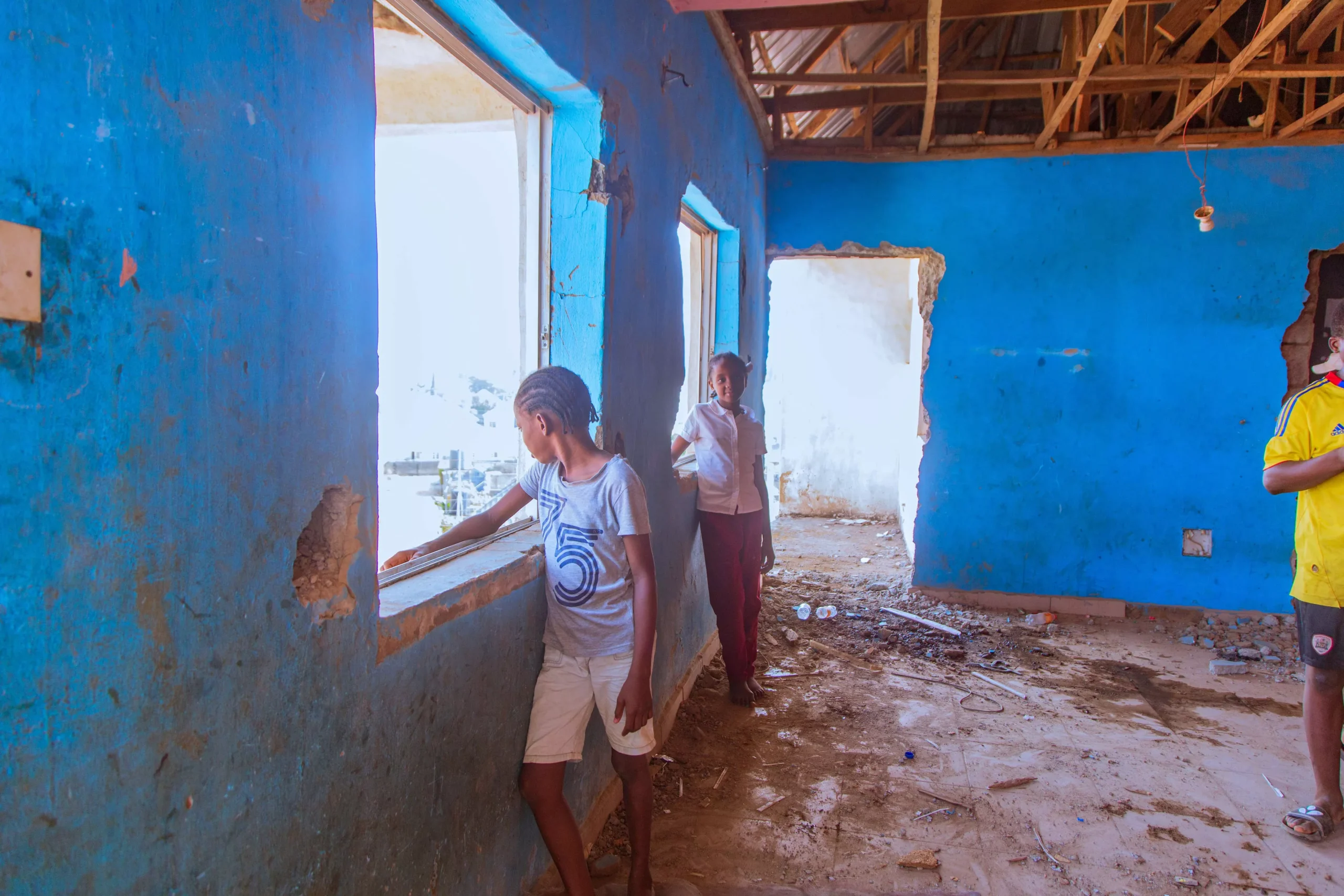 children inside damaged orphanage before charity renovation support